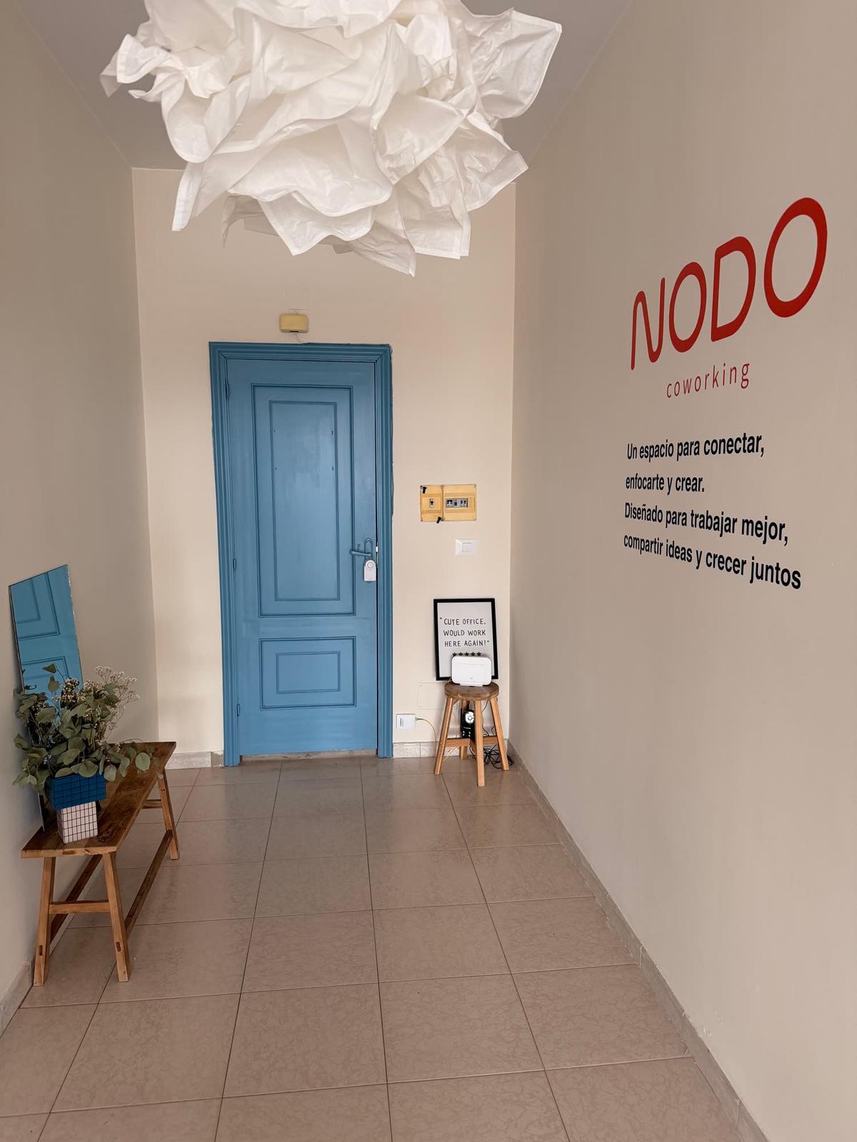 Entrada de Nodo con la puerta azul y el lema en la pared