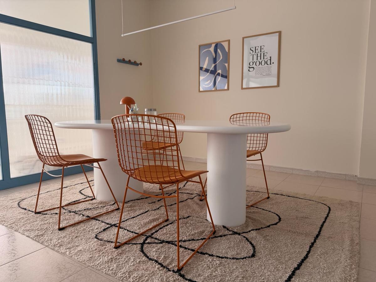 Sala de reuniones con mesa blanca orgánica y sillas naranjas
